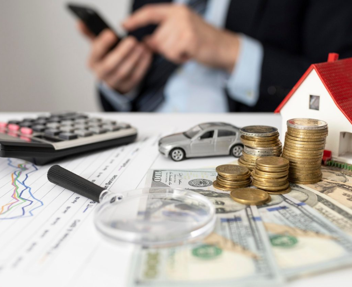 Planejamento financeiro com calculadora, miniaturas de casa e carro e moedas